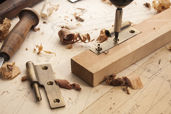 Carpenter with door hinge on a wooden plank